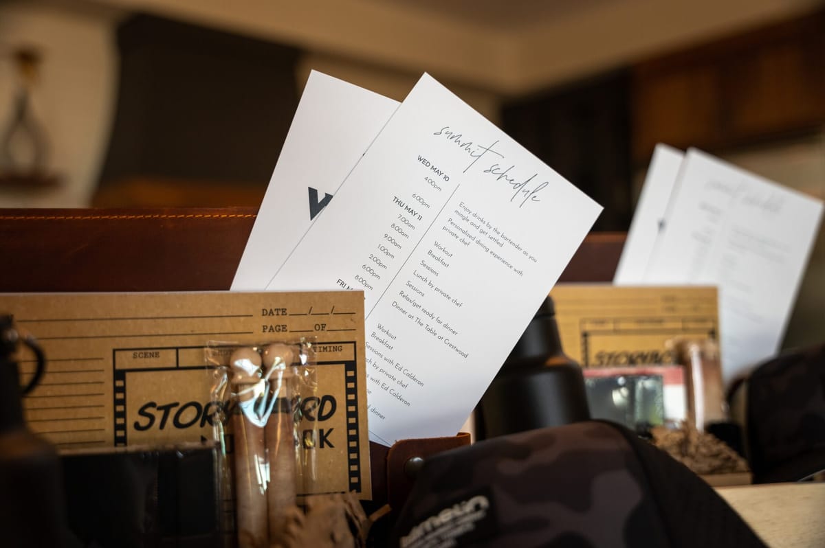 Summit schedule cards and Storyboard notebooks tucked into welcome gift boxes beside a camo cap