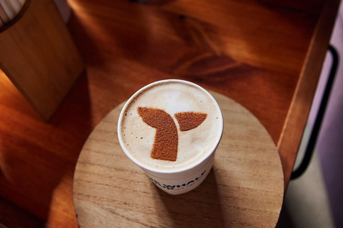 Latte in a Blue Whale Group cup with the whale tail logo dusted on the foam