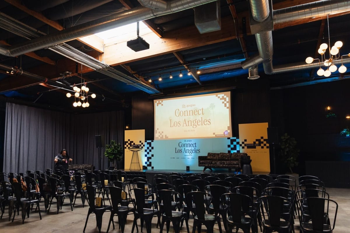Gorgias Connect Los Angeles stage with a color-blocked backdrop, checkerboard panels and rows of black chairs in an industrial venue