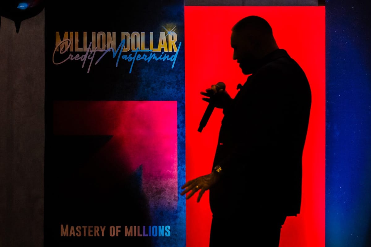 Speaker in silhouette with a microphone beside a Million Dollar Credit Mastermind, Mastery of Millions sign