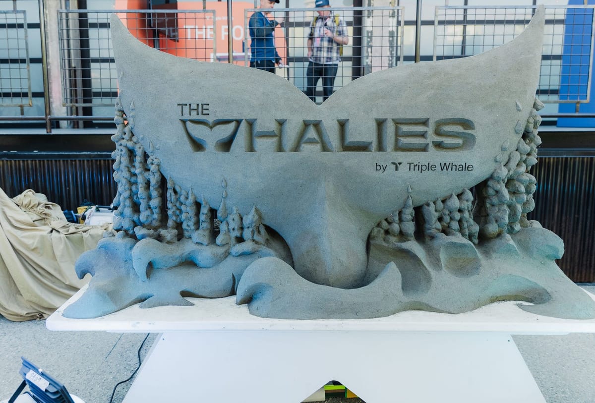 Sand sculpture of a whale tail carved with The Whalies by Triple Whale lettering