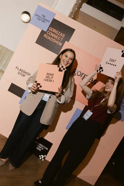 Two guests posing with signs against the coral and lilac colour-block wall