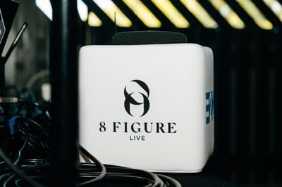 White microphone cube printed with the 8 Figure Live logo beside black cables