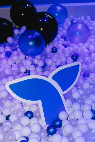 The blue Triple Whale tail mark lying in a pit of lilac and navy balls
