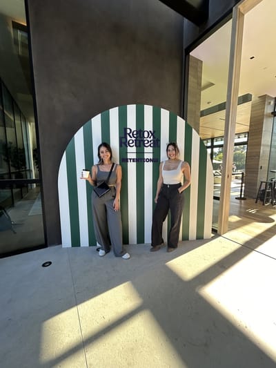 Samantha Pena and another woman in front of a green and white striped Retox Retreat arch