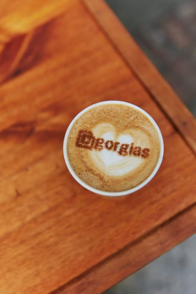 Latte with the Gorgias logo printed in the foam, on a wooden table