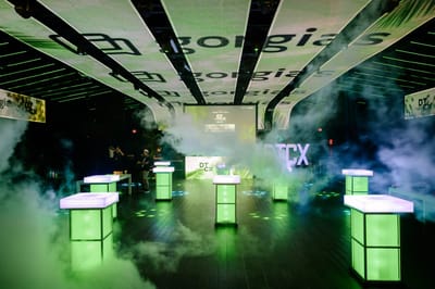 Glowing green cube tables in stage fog under LED ceiling panels showing the gorgias logo
