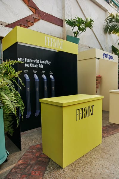 The chartreuse Fermat stall with acrylic funnels mounted on a black wall reading Create Funnels The Same Way You Create Ads
