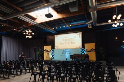 Gorgias Connect Los Angeles stage with a color-blocked backdrop, checkerboard panels and rows of black chairs in an industrial venue
