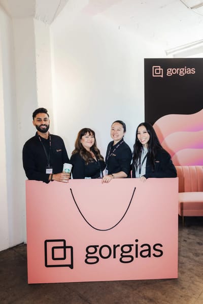 The Gorgias team working behind the oversized coral shopping bag desk
