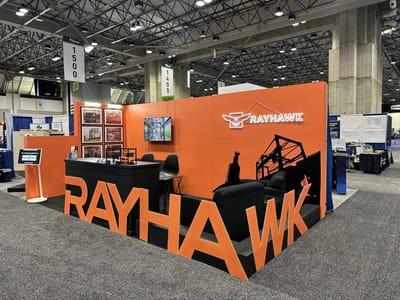 The Rayhawk booth with giant orange dimensional letters wrapping a lounge