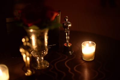 Candlelit table with red roses in a glass vase and a small gold statuette