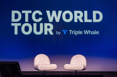 Two white egg-shaped chairs on a stage below a blue screen reading DTC World Tour by Triple Whale