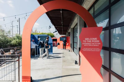 A coral arch reading Welcome To The Pods at the entrance to the courtyard