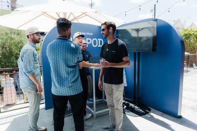 Guests talking outside the blue Pod under string lights