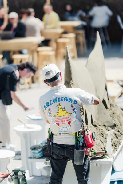 Sculptors shaping the fins out of raw sand beside the finished piece