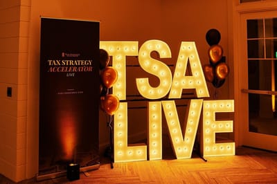 Light-up TSA LIVE marquee letters beside a Tax Strategy Accelerator Live banner and black and gold balloons