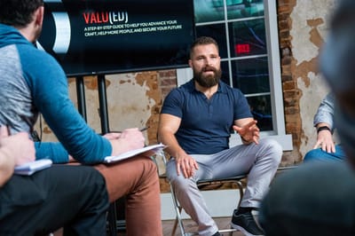 The presenter talking with seated attendees below a screen reading Valu(ed), a step-by-step guide to help you advance your craft