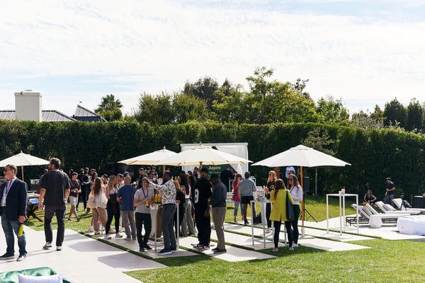 Crowd of guests on the lawn among white umbrellas and high tables