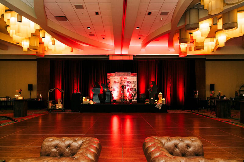 Dance floor facing a stage lit with red light and drapes, leather sofas in the foreground