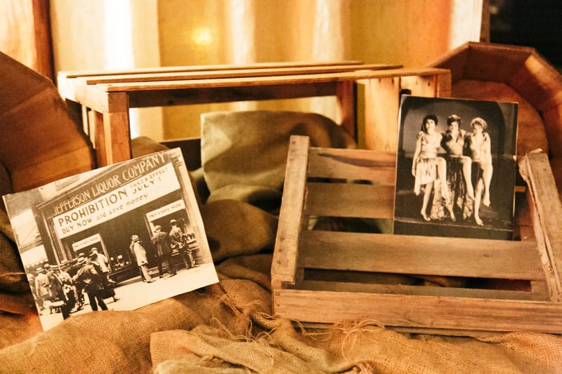 Old photographs of the Jefferson Liquor Company and three women in 1920s dress propped in wooden crates on burlap
