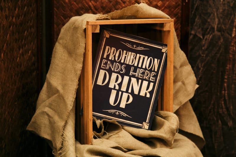 Sign reading Prohibition Ends Here Drink Up in a wooden crate draped with burlap