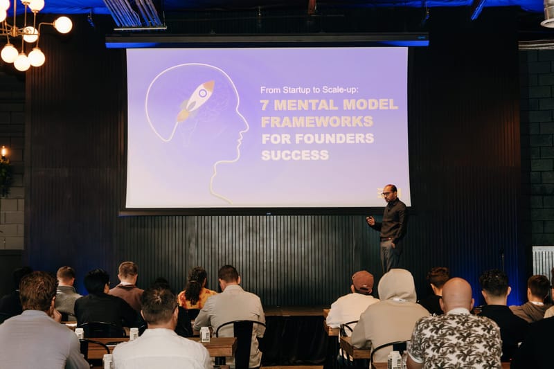 Speaker presenting 7 Mental Model Frameworks for Founders Success to a seated audience