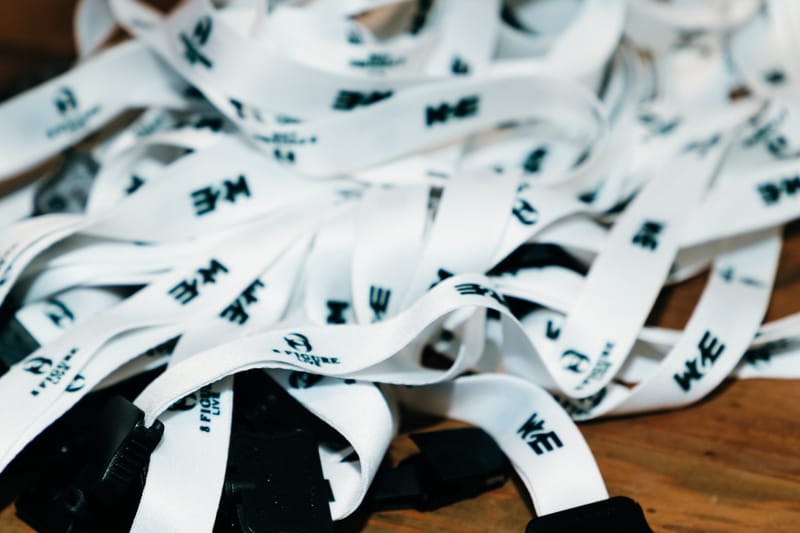 Pile of white lanyards printed with the 8 Figure Live and E2M logos