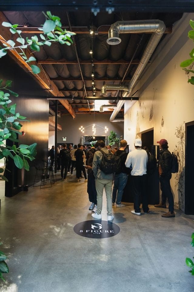 Attendees gathering in a hallway beside an 8 Figure floor logo