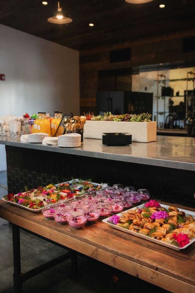 Catering display of pastries and fruit decorated with pink flowers