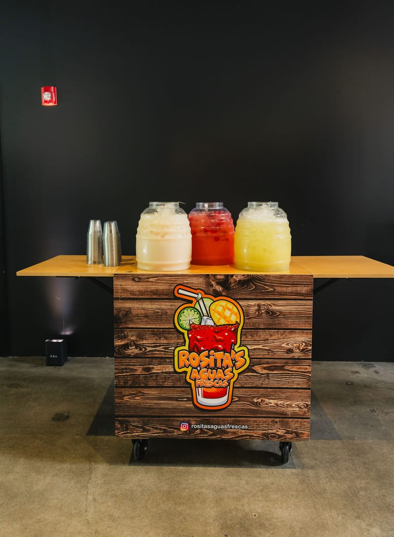 A Rosita's Aguas Frescas cart with three jars of agua fresca and stacks of cups
