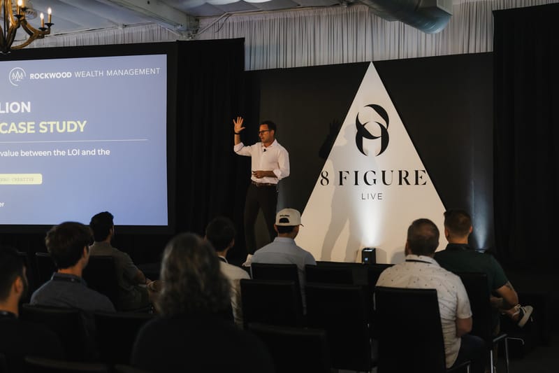 Speaker gesturing on stage beside a case study slide