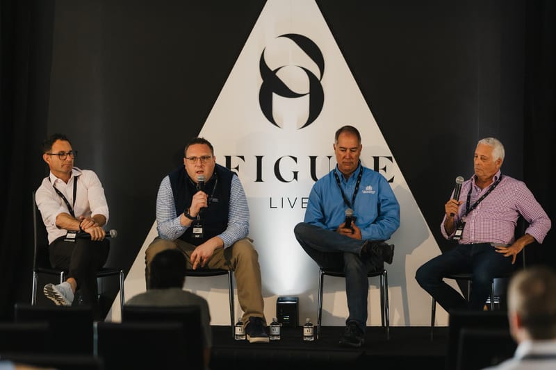 Four panelists with microphones seated in front of the 8 Figure Live triangle backdrop