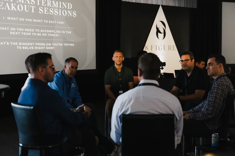 Small group in a breakout circle beneath a screen of mastermind discussion questions