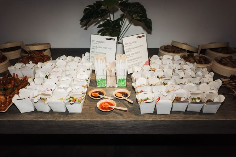Happy hour food boxes, dumplings in bamboo steamers and sauces beside Happy Hour menu cards