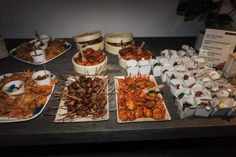 Platters of wings, skewers and shrimp beside bamboo steamer baskets