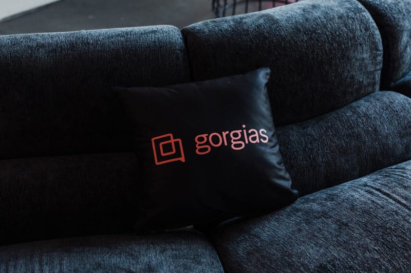 Black pillow printed with the Gorgias logo resting on a dark sofa
