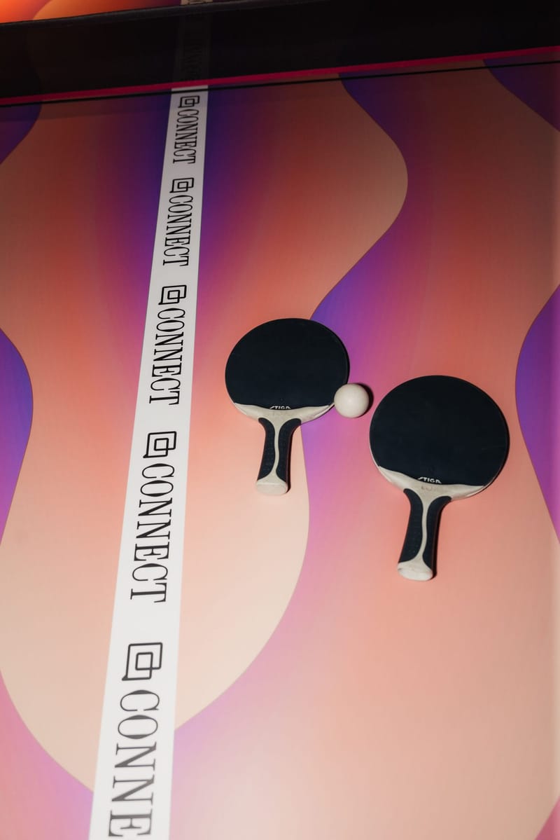 Two ping pong paddles and a ball mounted on a pink and purple wall with a Connect strip