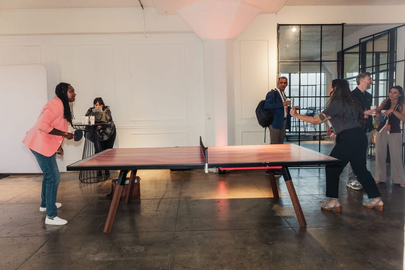 Guests playing ping pong in a bright white loft