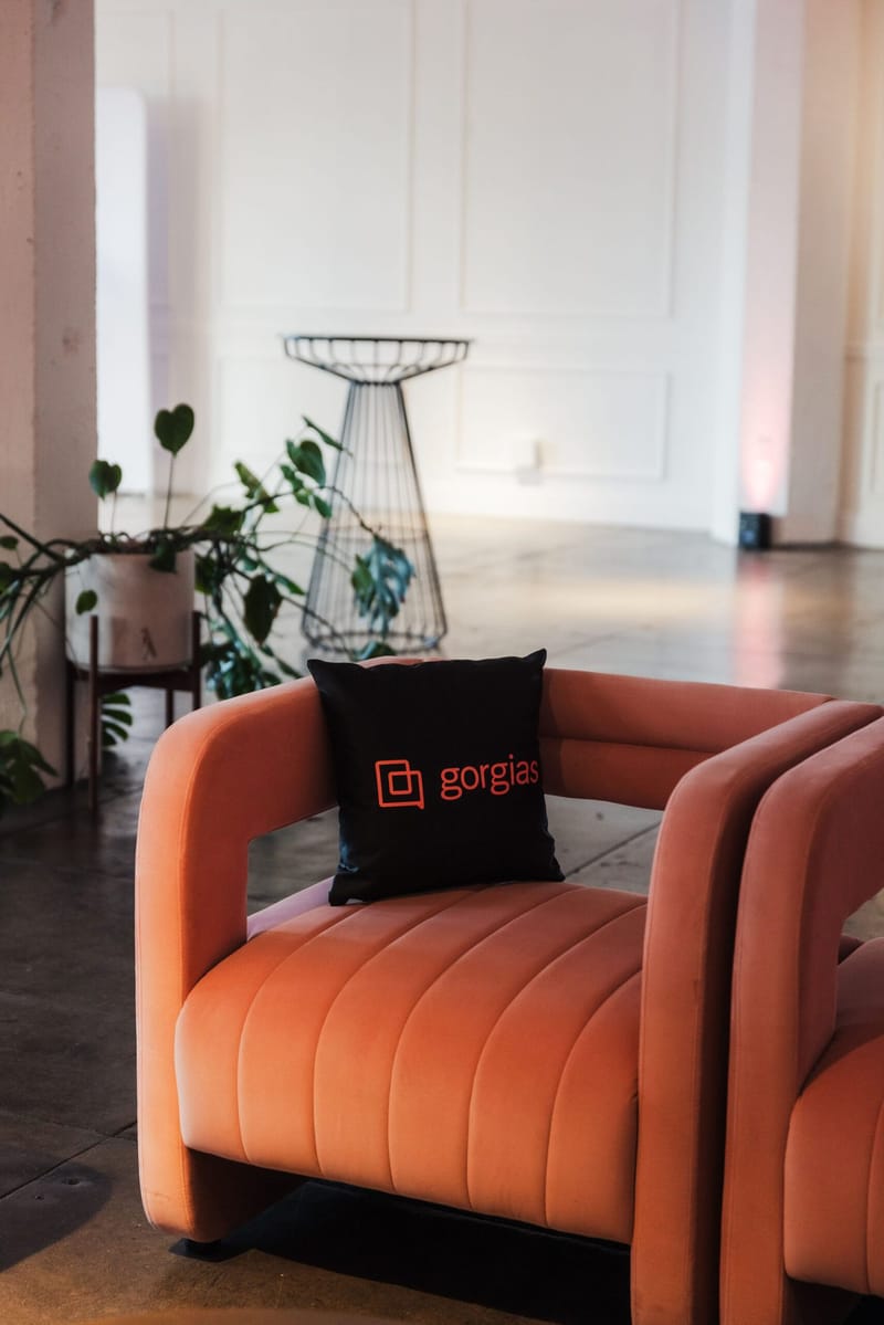 Orange velvet armchair with a black Gorgias pillow