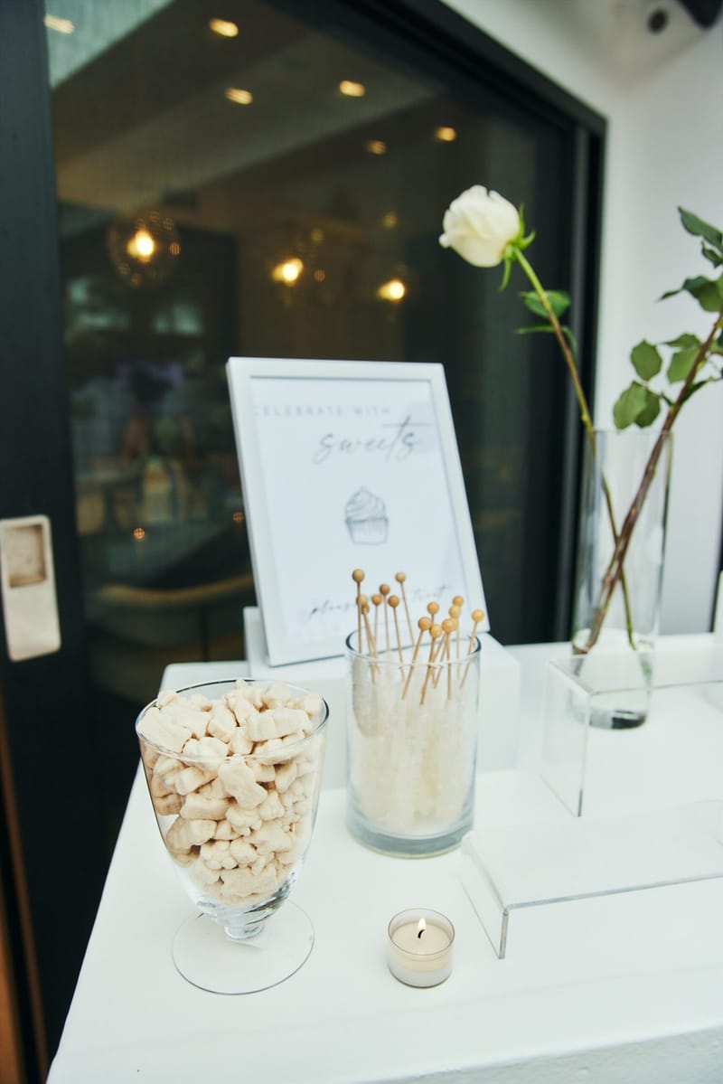 Celebrate with sweets sign behind a glass of rock candy sticks, a bowl of cream candies and a tealight
