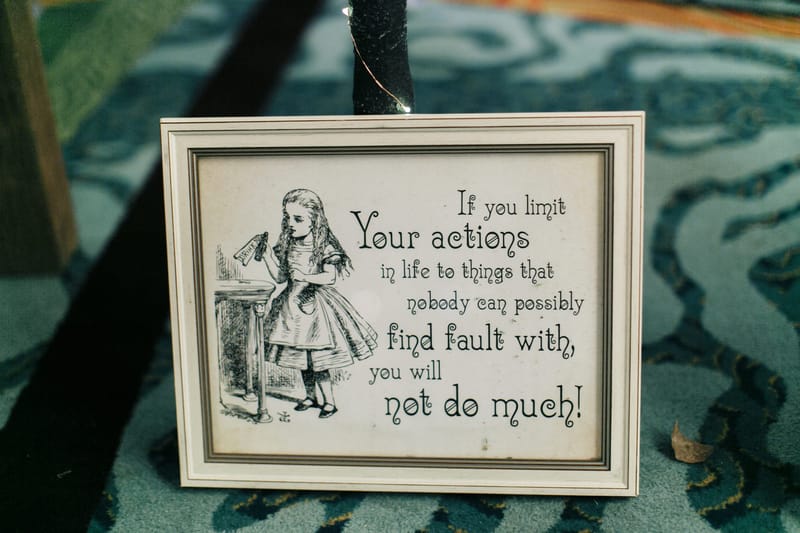 Framed Alice illustration with a quote beginning If you limit your actions in life, on a patterned carpet