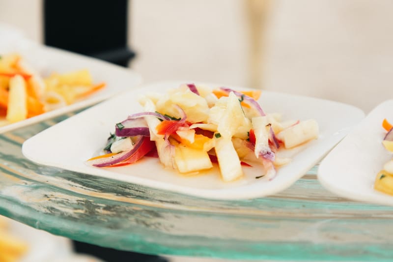 Charred pineapple salad with red onion on a small square white plate