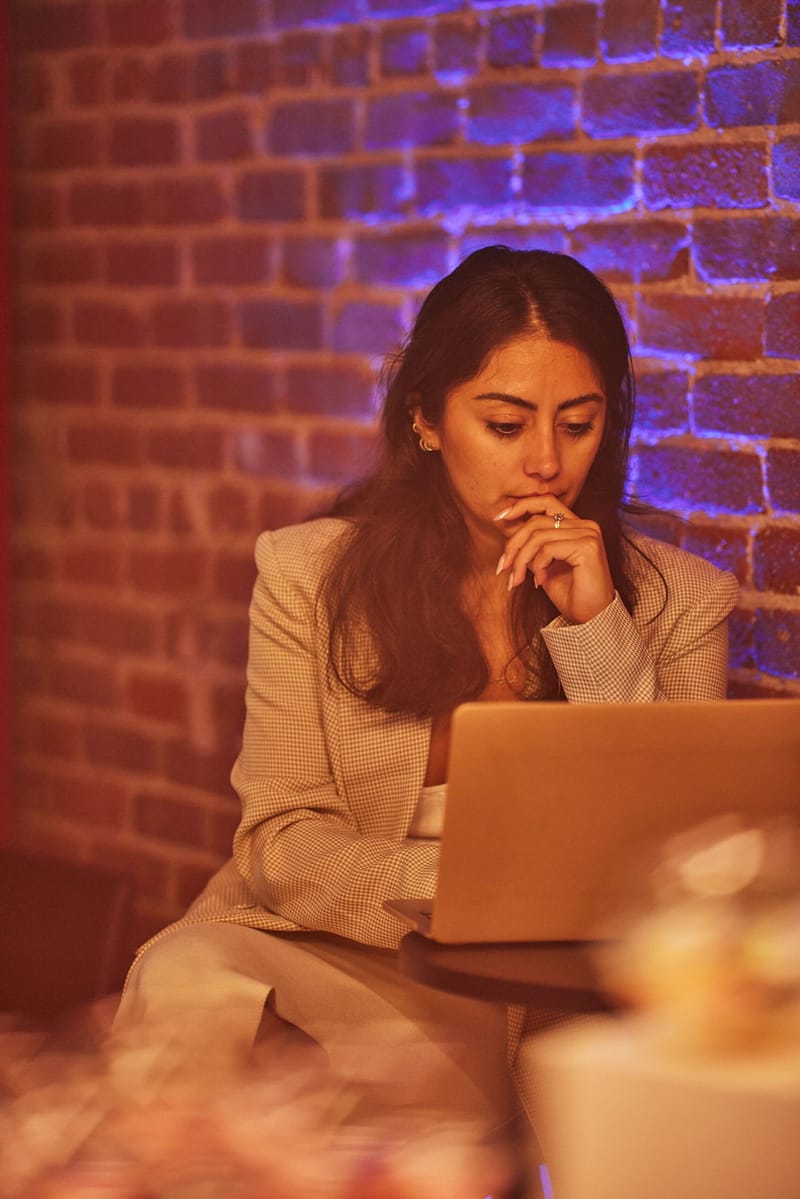 Attendee working on a laptop against a brick wall washed in purple light