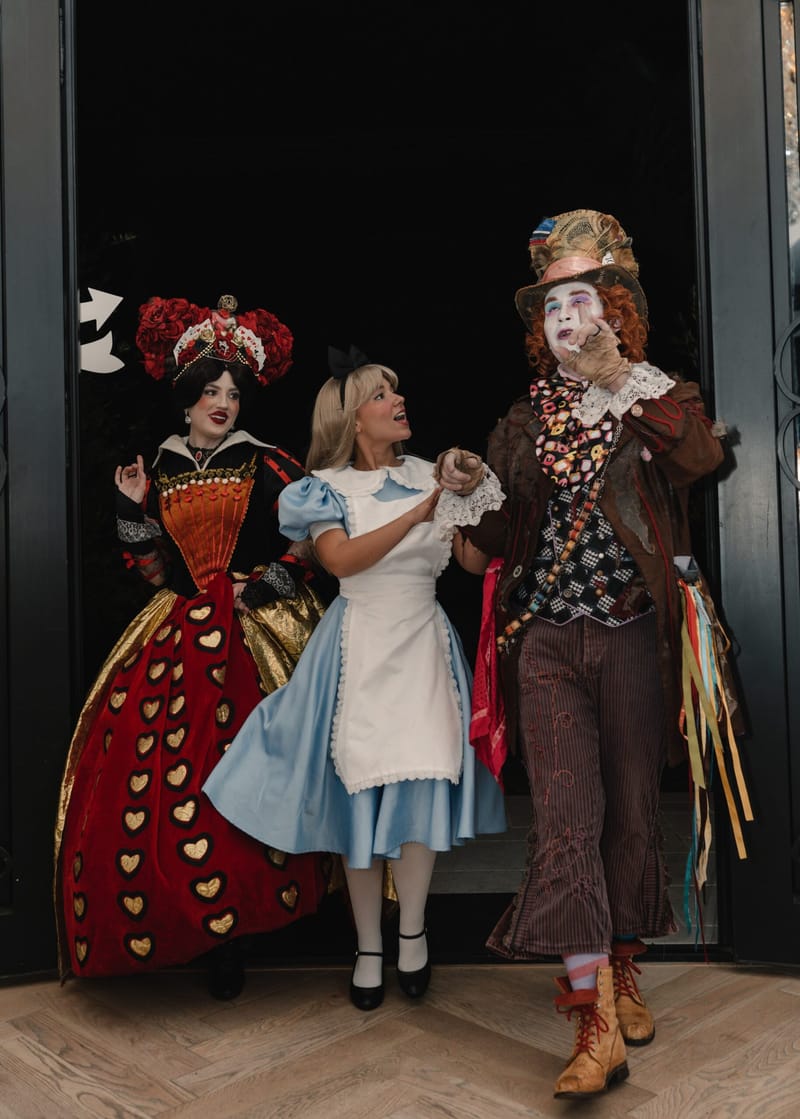 The Queen of Hearts, Alice and the Mad Hatter walking in through a doorway