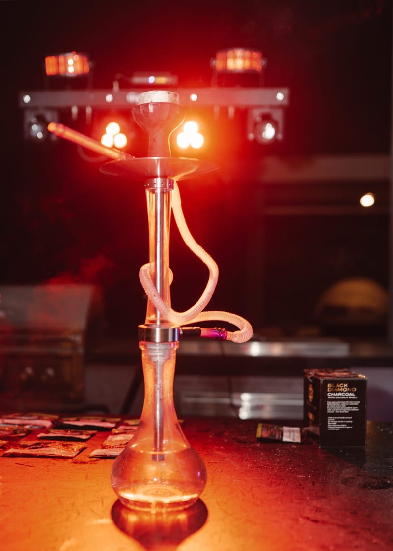 Glass hookah glowing under red stage lights on a table