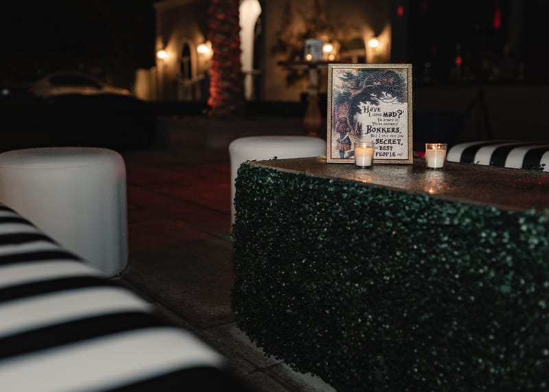 Framed Have I gone mad? quote sign with votive candles on a hedge-covered cocktail table