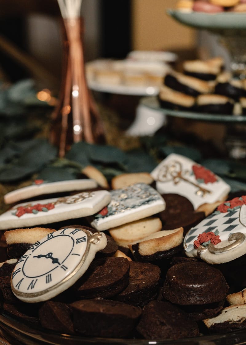 Cookies iced as a clock face and antique keys on a plate of brownies