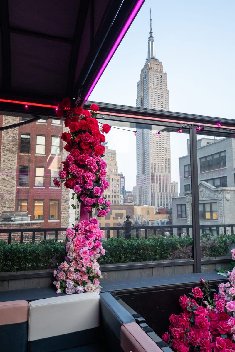 Column of pink and red roses at a rooftop rail with the Empire State Building behind