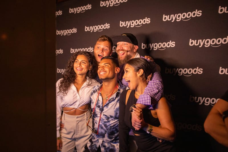 Four guests posing together in front of a buygoods logo backdrop